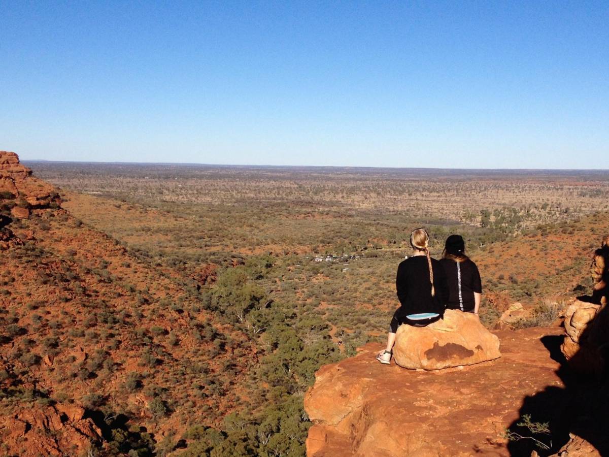 two students sitting atop a mountain in the outback