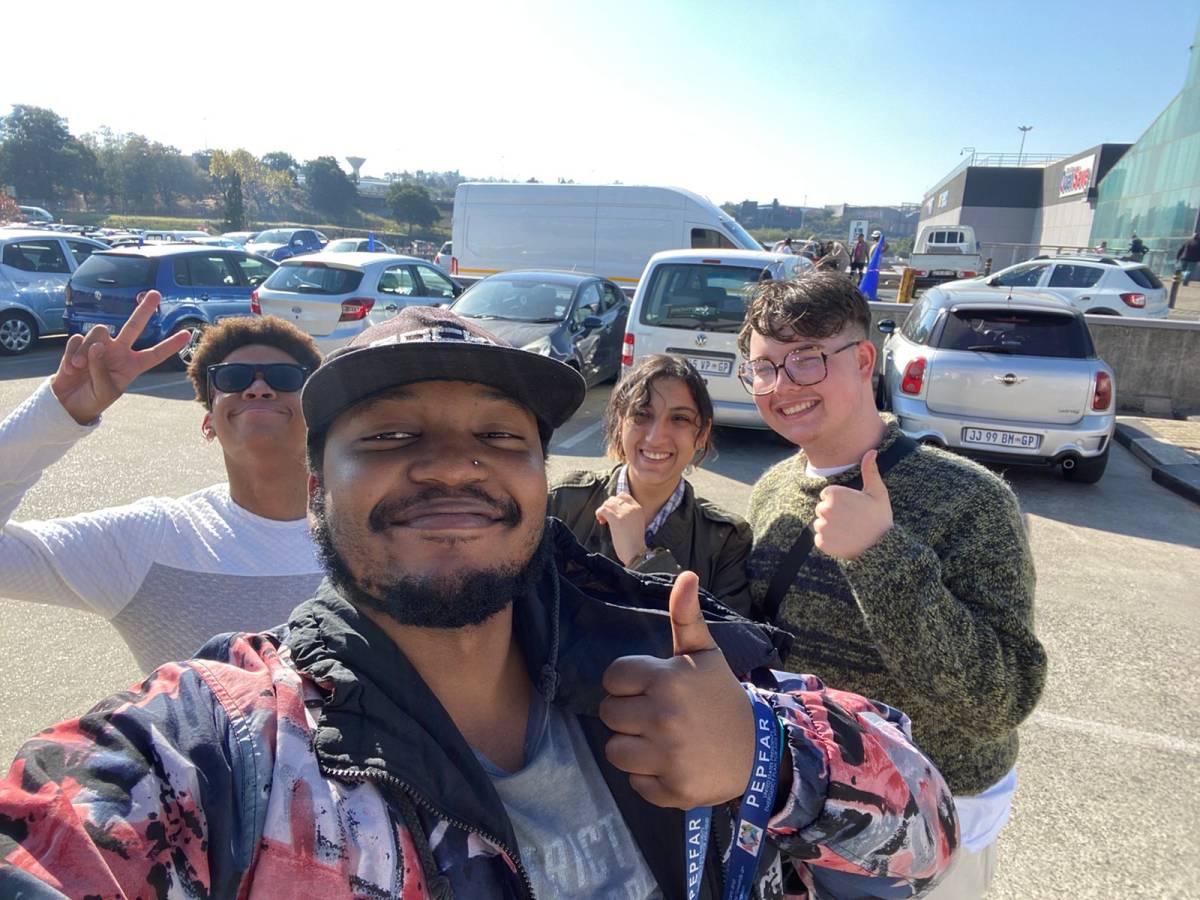 Two volunteers and two members of staff smile into the camera and give an enthusiastic thumbs up