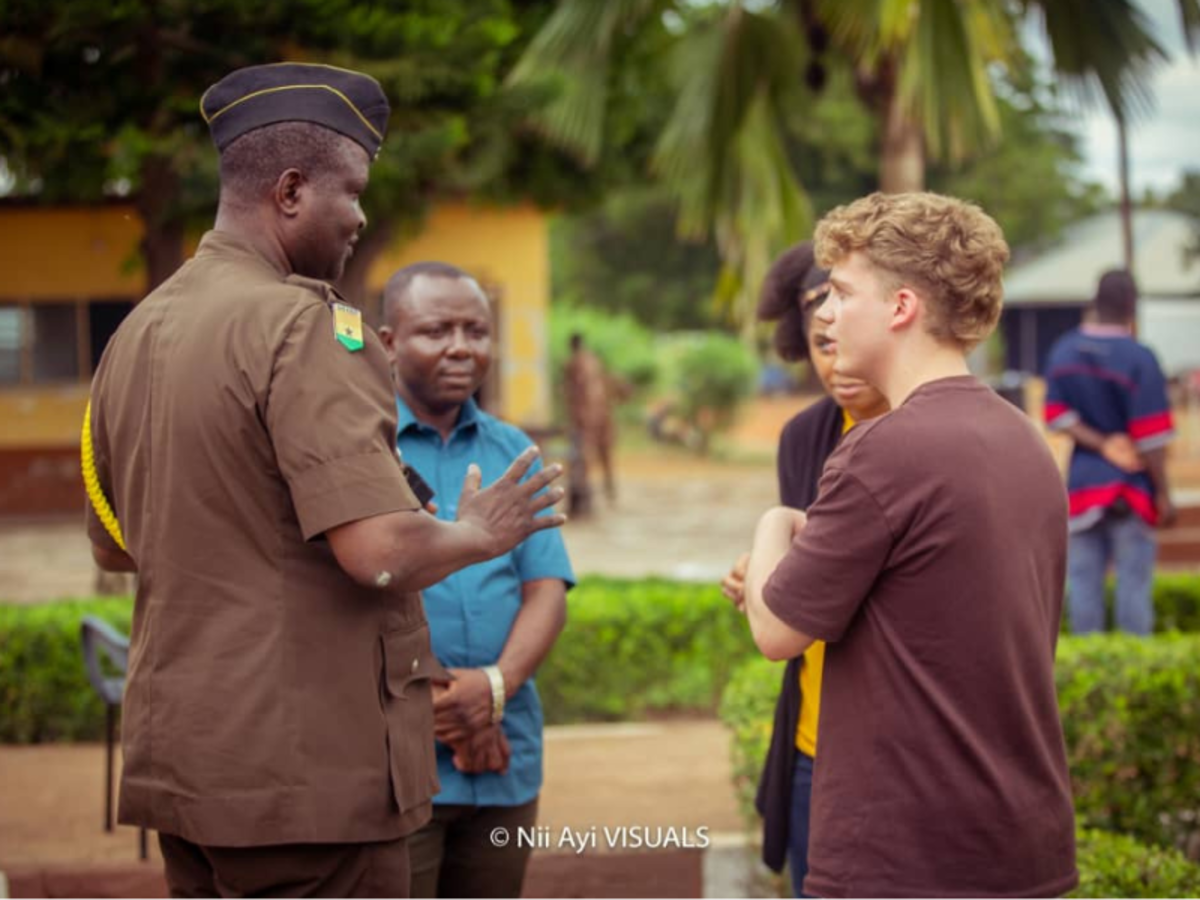 Two volunteers are deep in conversation with a prison official in his brown uniform, while the programme co-ordinator listens intently.