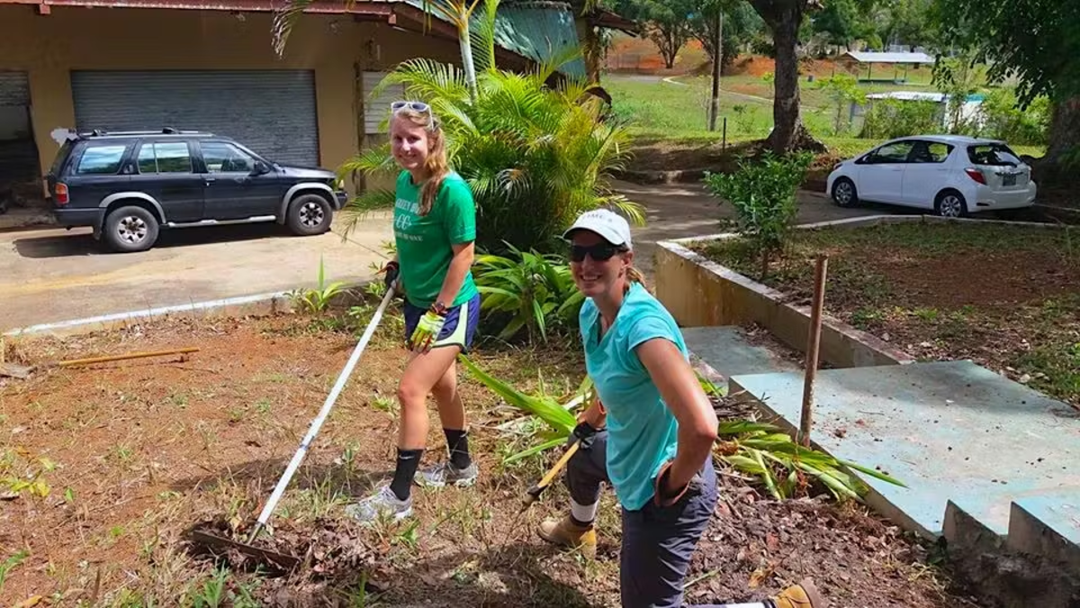 Two volunteers working outdoors clearing vegetation