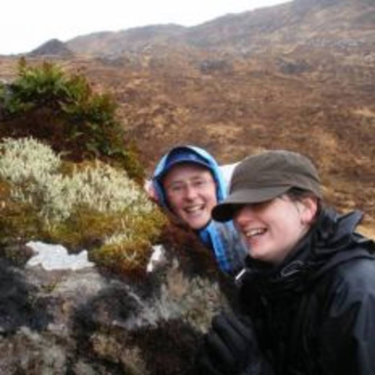 Two women smiling and posing for a picture on a rock.