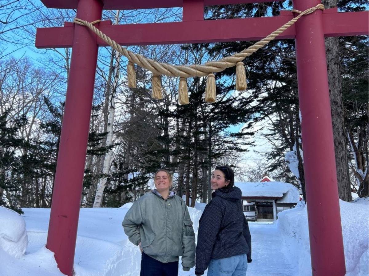 Two women standing under a torii gate in Japan