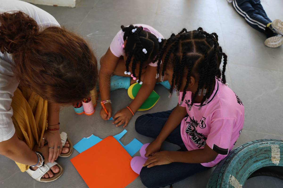 volunteer and children cutting colored paper