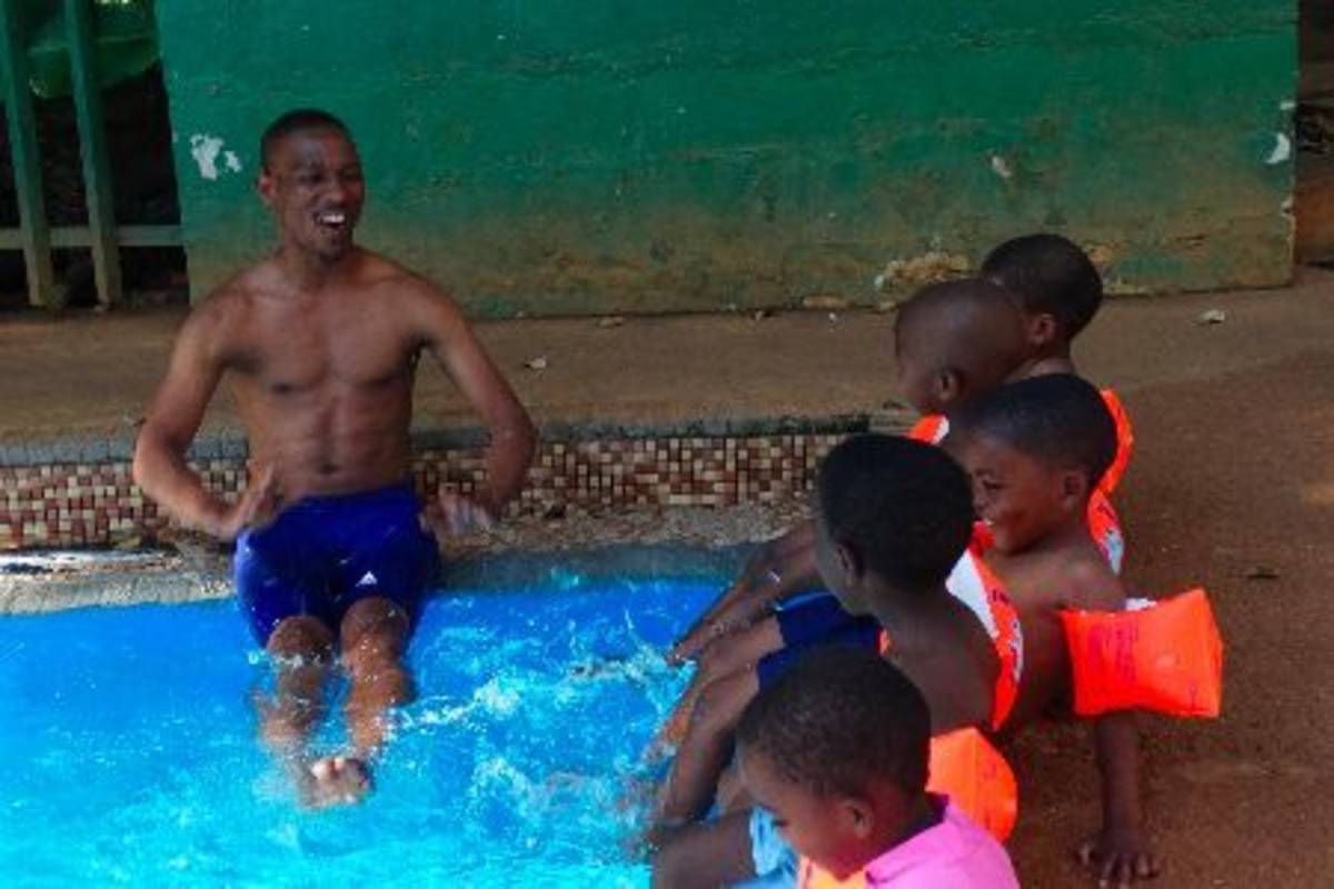 volunteer and children practice kicking in the pool