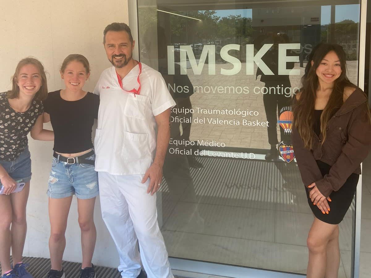 Volunteers stand with a doctor outside of a hospital.