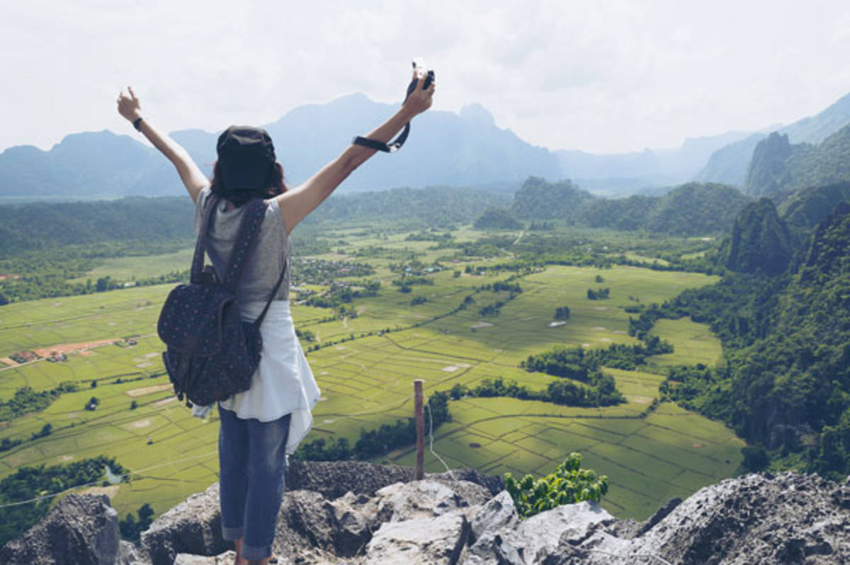 Woman raises her hands in the air as she looks at the view