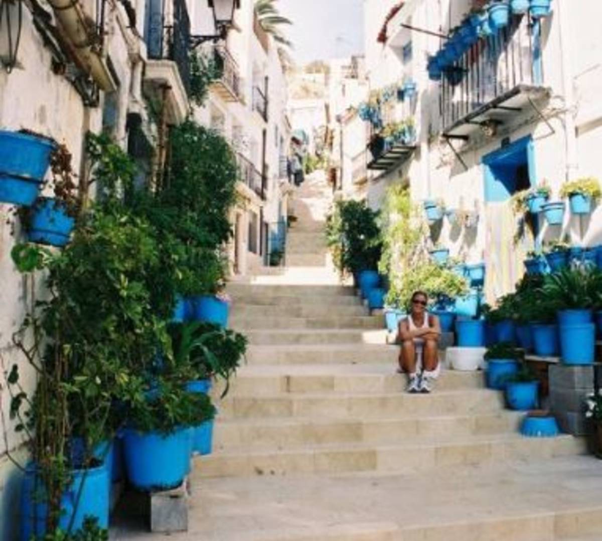 Woman sitting on stairs with plant-decorated house