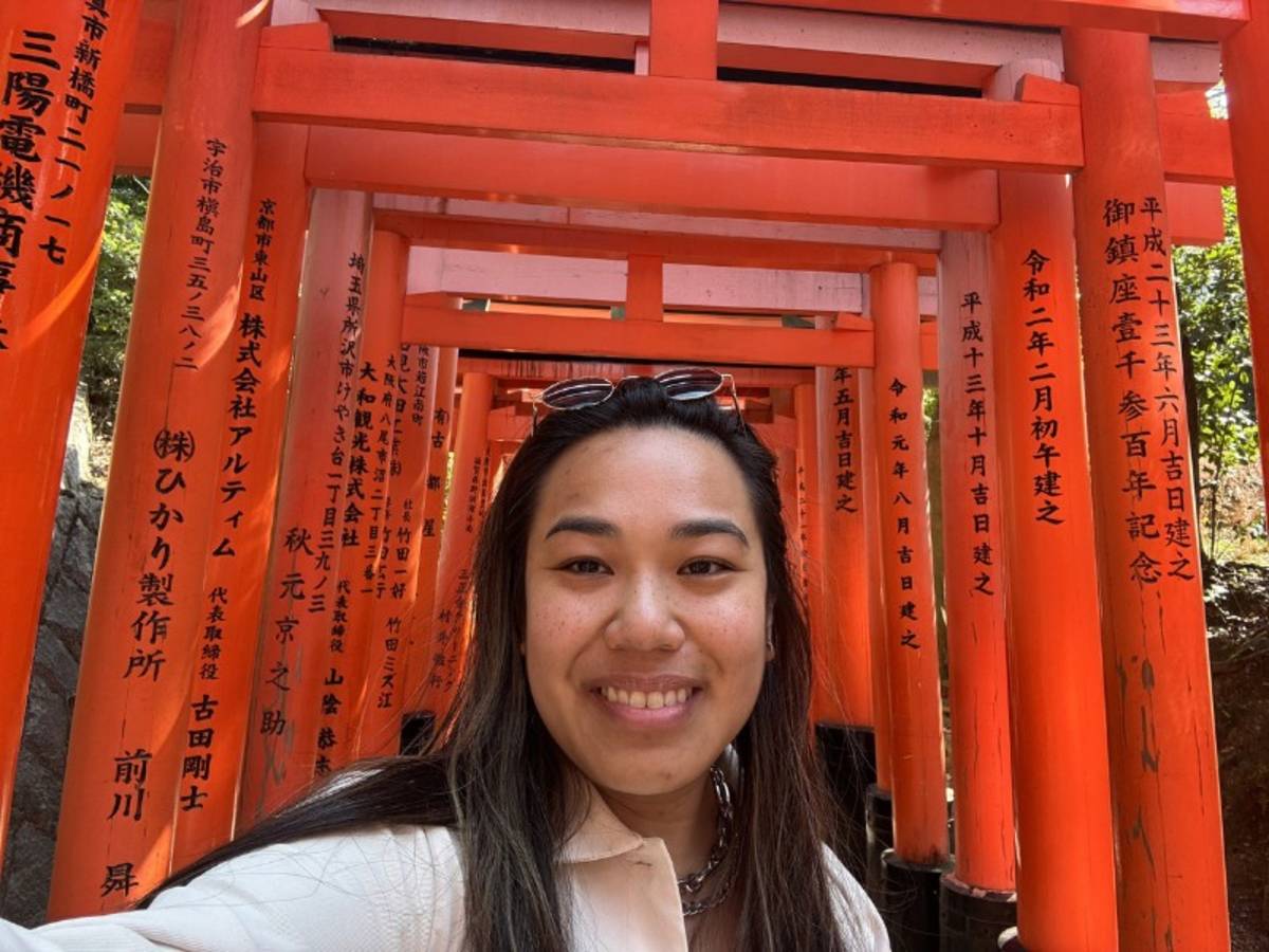 Women smiles while taking selfie in from of Fushimi Inari Taisha shrine in Kyoto, Japan.