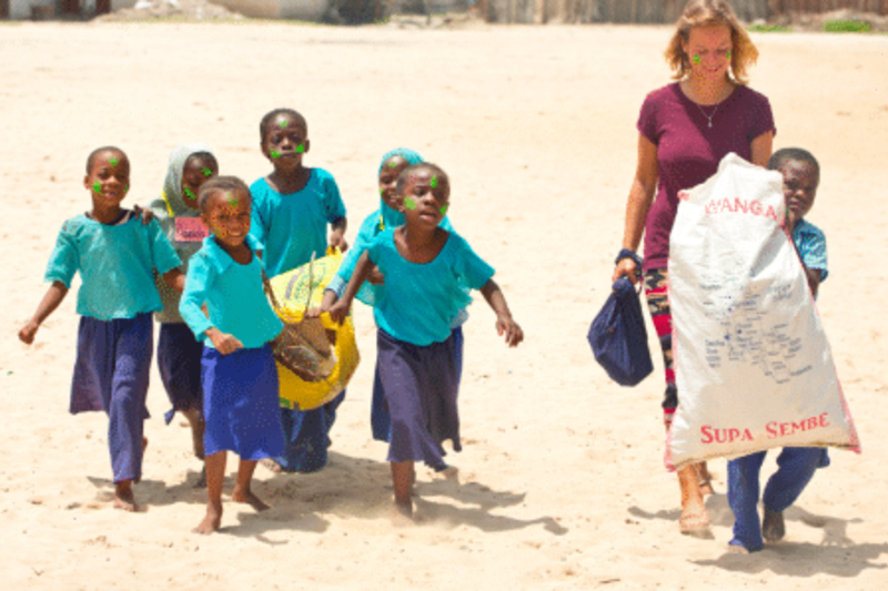 An image of a volunteer with kids on beach