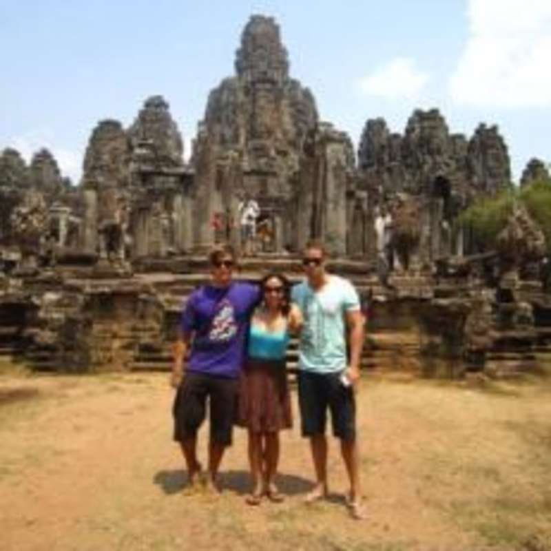 3 people posing in front of ancient Thai Temple
