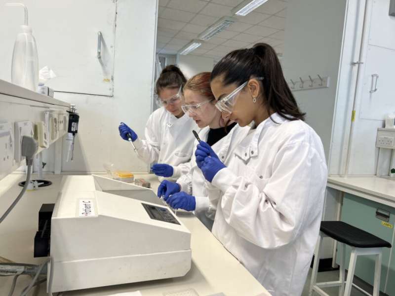 3 students using lab equipment in lab coats