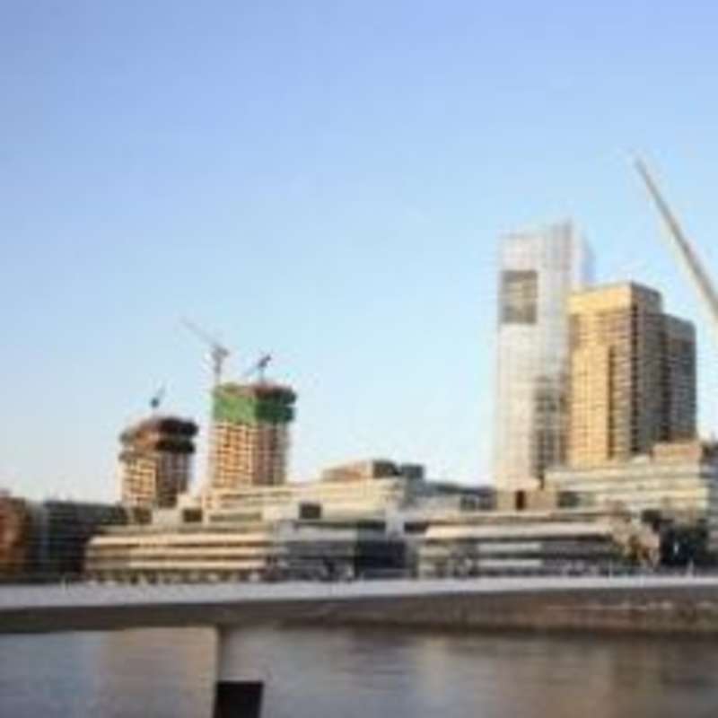 A bridge spanning a river with towering buildings in the backdrop.