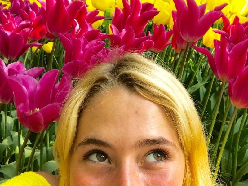 A closeup of a student sitting in a field of tulips in Amsterdam.