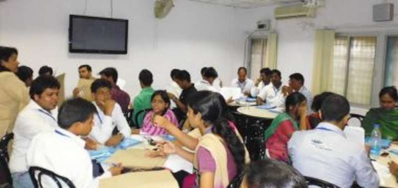 A diverse group of individuals sitting at tables in a classroom.
