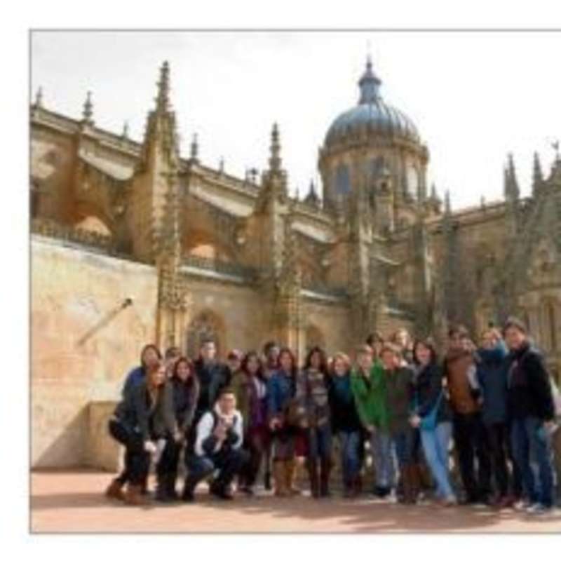 A diverse group of people smiling in front of a majestic cathedral.