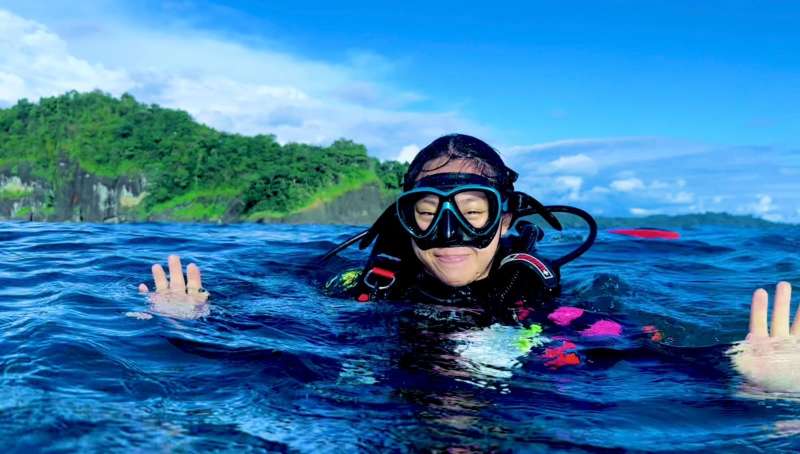 a girl smiles with googles in the ocean