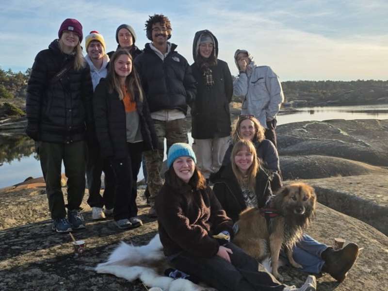 a group of college students pose together smiling while wearing cold weather gear