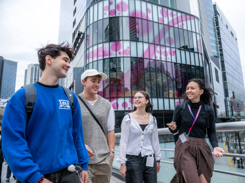 A group of EF Tokyo students walking together and smiling in a lively modern district of the city.