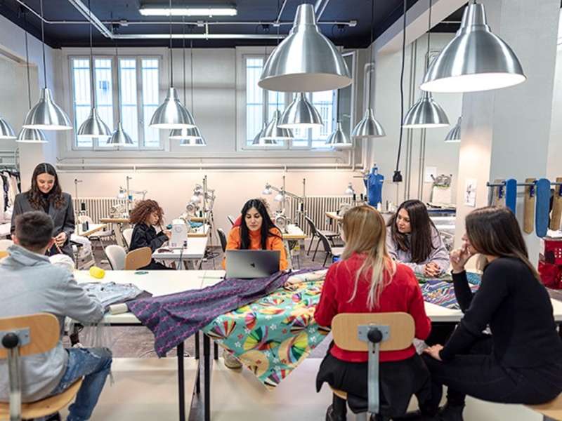 A group of fashion design students sat around a table working.