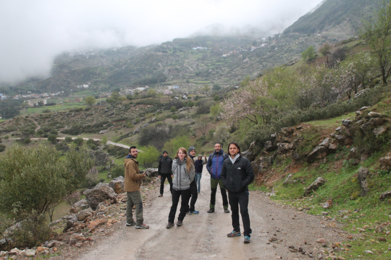 a group of people hiking on a dirt path in a mountainous region