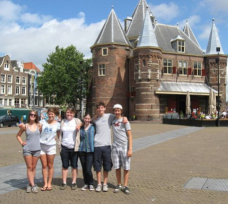 A group of people smiling and posing in front of a building