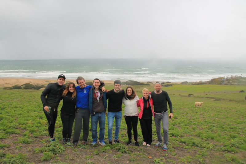 a group of people standing on a green field with a foggy ocean in the background