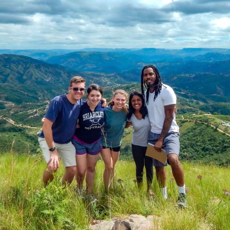 A group of SIT students huddled together on top of a mountain in South Africa.