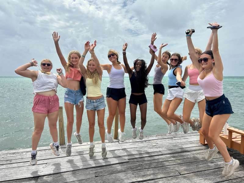 A group of teens jump on a boardwalk next to the ocean in Belize