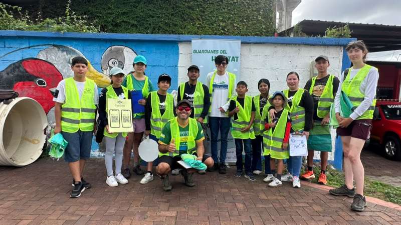 A group of young people wear safety vests and pose for a photo.