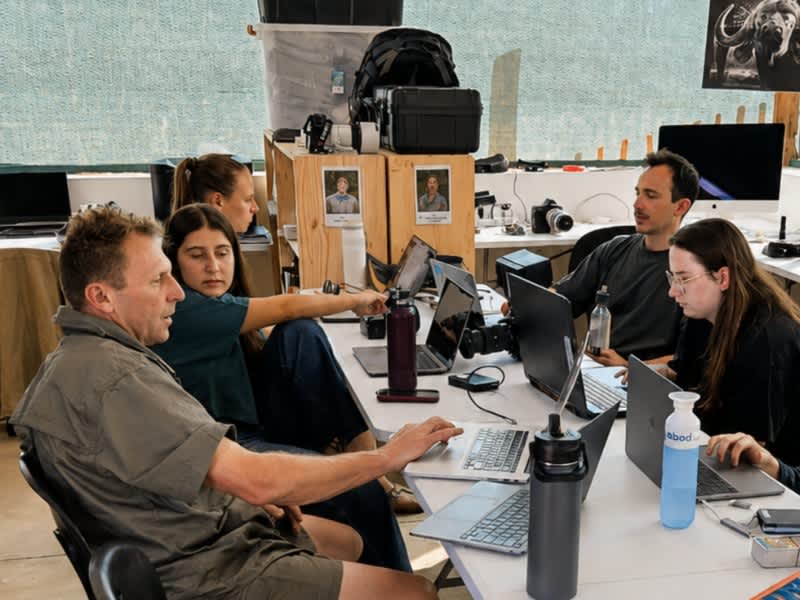 A group reviewing photos on laptops together in a classroom in Kruger on a Penda Photo Tour