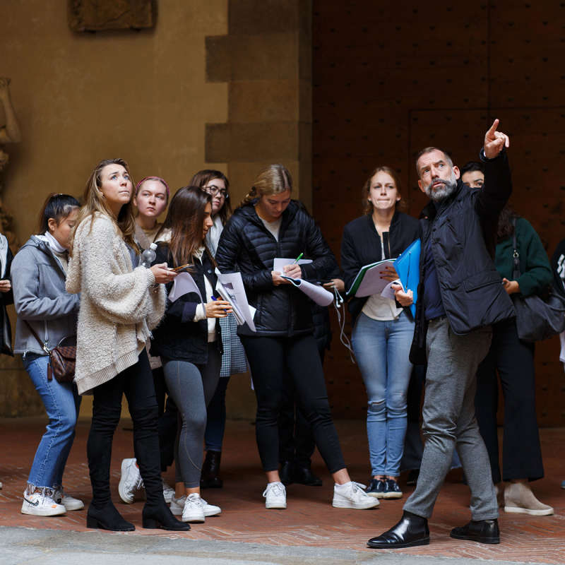 A professor points out a detail to students taking notes.