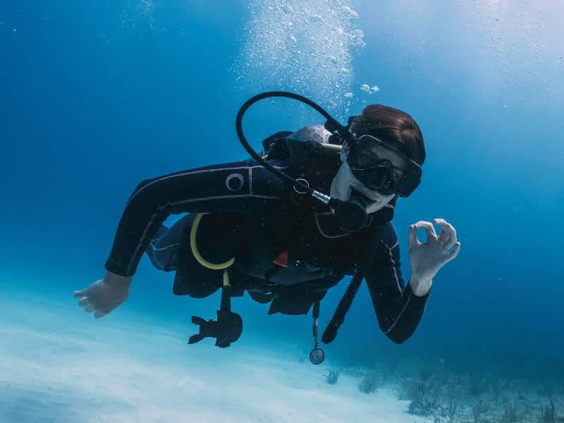 A scuba diver giving the OK hand signal over a sandy seabed on a South Africa Penda Photo Tour