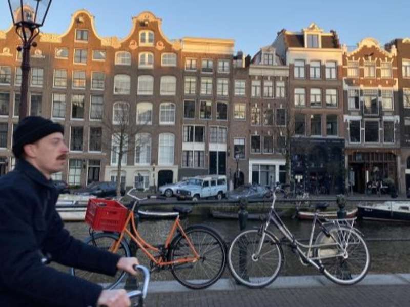 A student bikes next to a canal in Amsterdam.