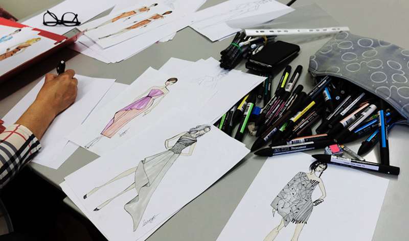 A student doing design sketches with materials on the table