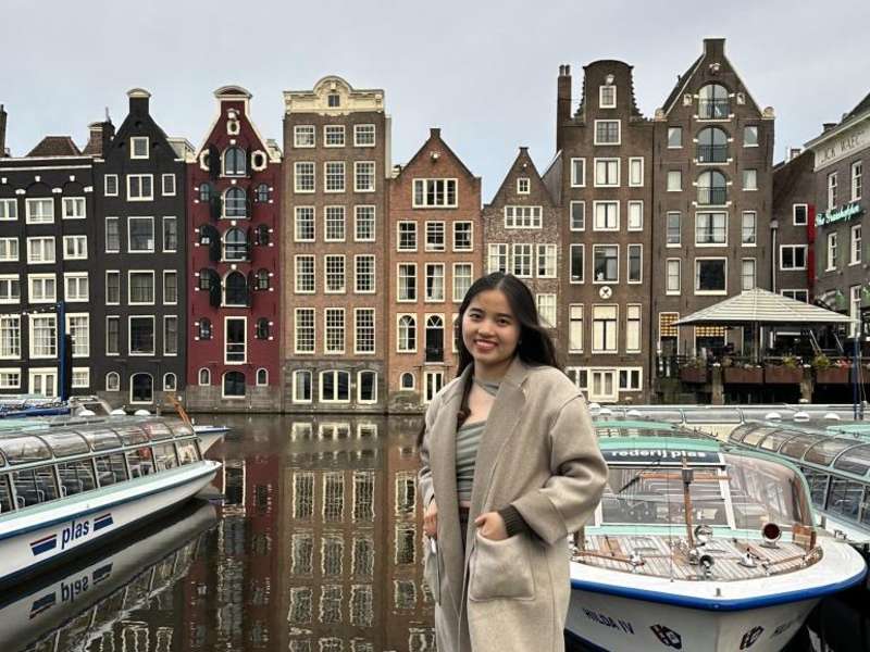A student poses in front of a canal in Amsterdam.