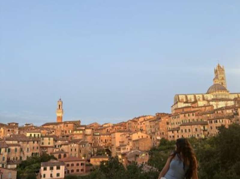 A student sits at an overlook over the city of Siena, Italy.