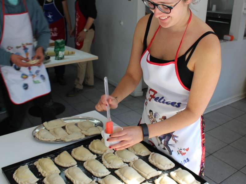 a student wearing an apron and preparing Chilean empanadas