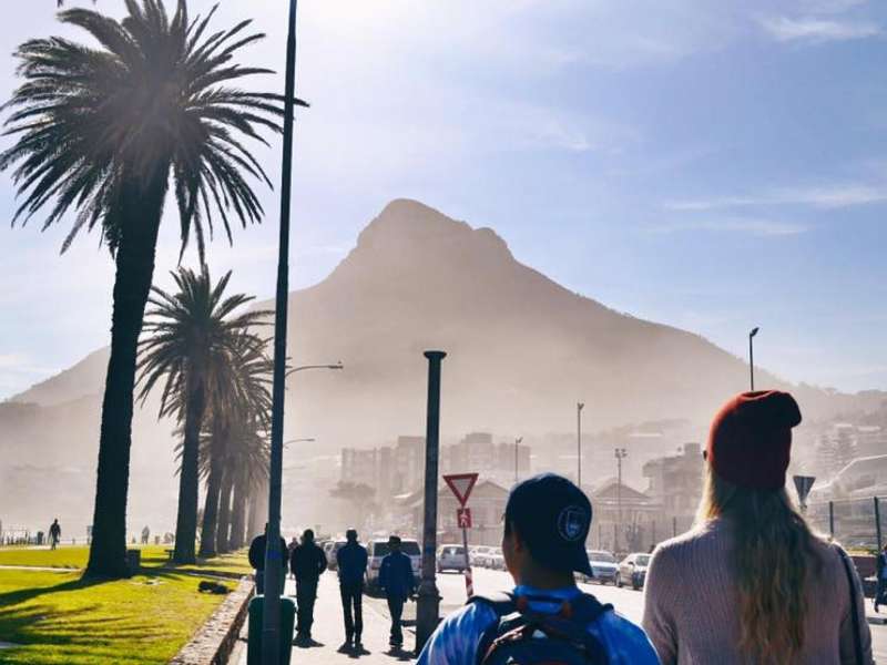 A sunny day where people walk Cape Town's beachside promenade.