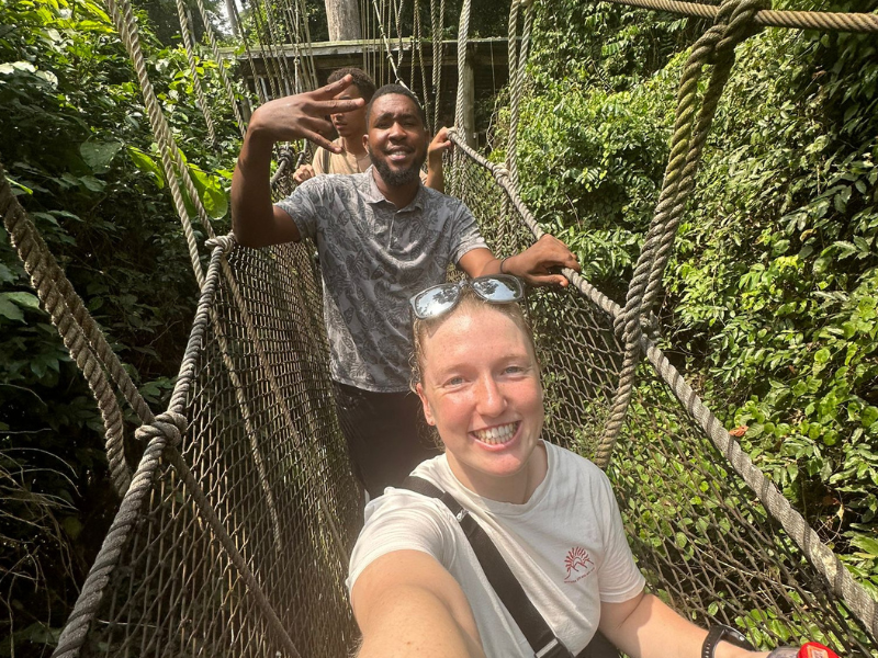A volunteer and the team take a selfie on a rope bridge in the jungle canopy.