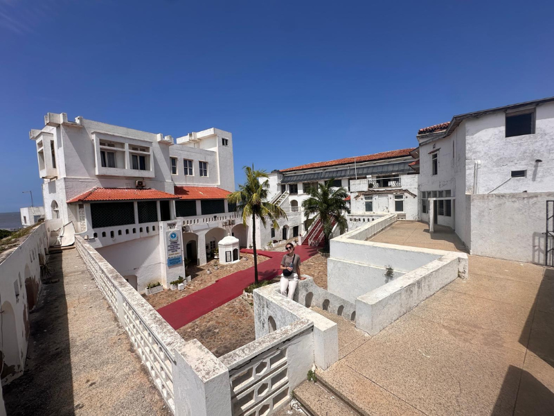 A volunteer stands in the courtyard of the bright white Cape Coast Castle, taking in the history.