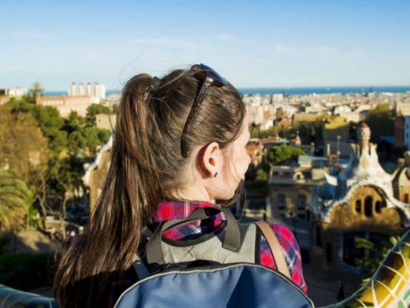 A woman with a backpack admiring the cityscape from a scenic viewpoint.