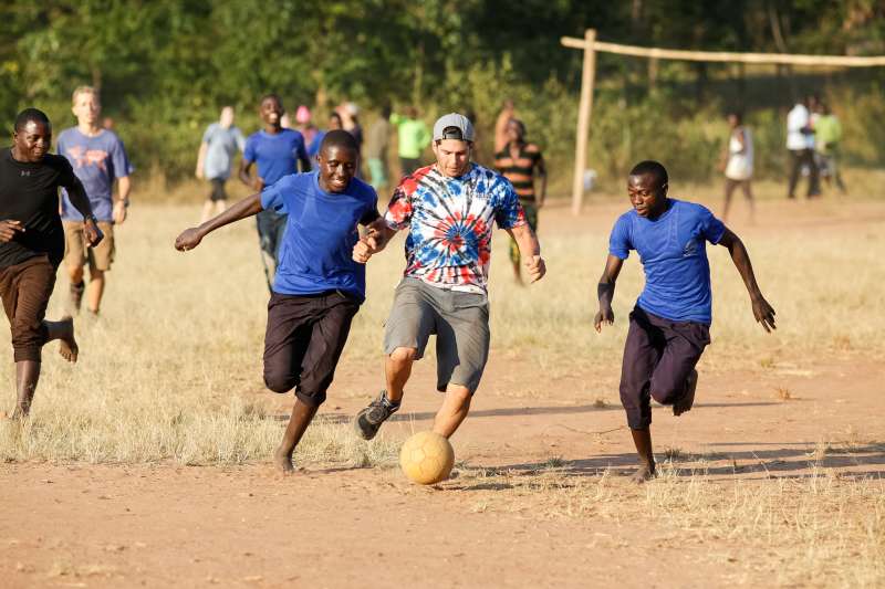 Boy playing soccer with locals in Tanzania
