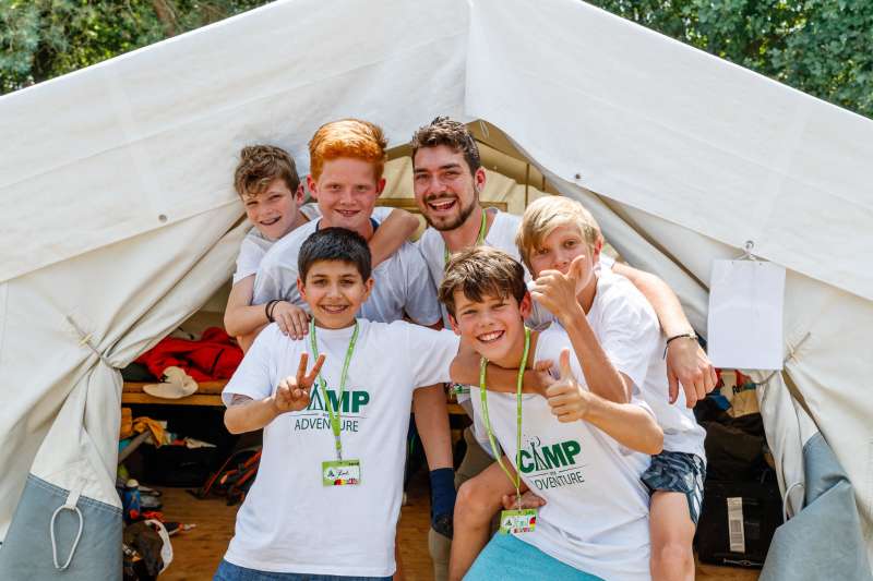 Children and camp learner smile in front of an activity tent