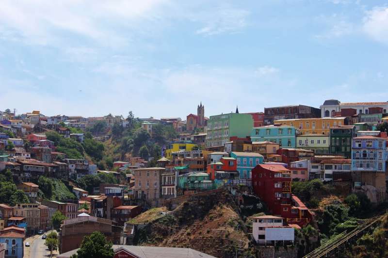 Colorful hillside buildings of Valparaíso, Chile, overlooking the Pacific Ocean and bustling port below.