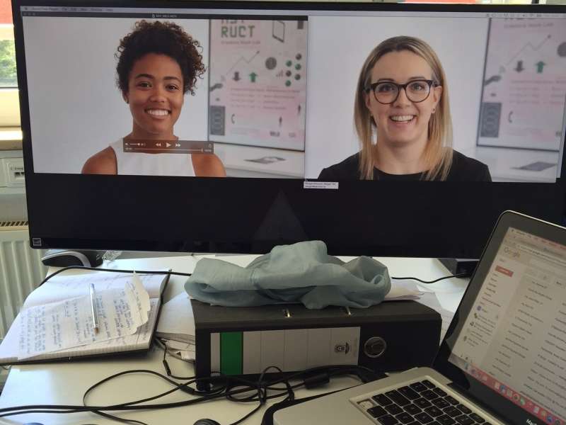 Computer screen with two faces on video at a desk