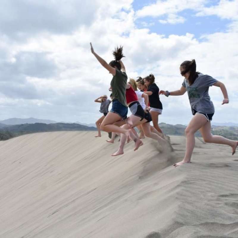 teens running down a sand dune in Fiji