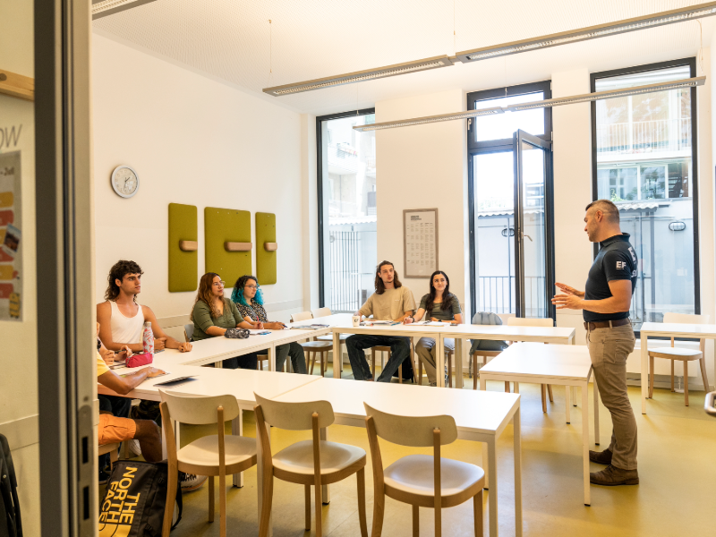EF students sit in a bright classroom in Berlin, listening to their teacher at the front of the room.