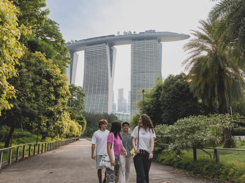 EF students walking together in Singapore with Marina Bay Sands in the background, surrounded by lush greenery.