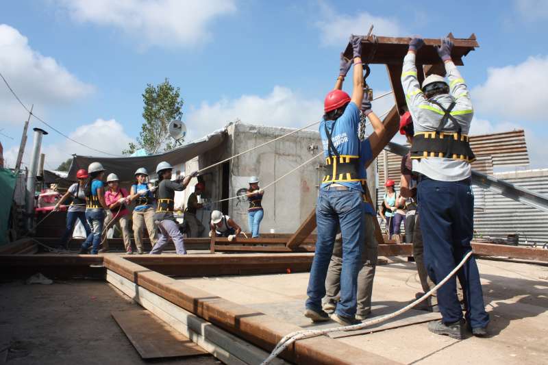 Engineering volunteers raising metal structure at community project