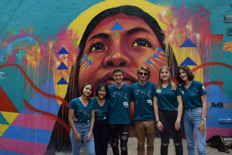 exchange students enjoying their time in Colombia while in front of a city mural